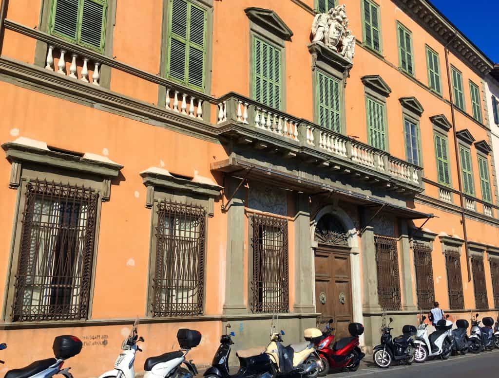 One day in Pisa: Terracotta building with motorcycles outside in Pisa