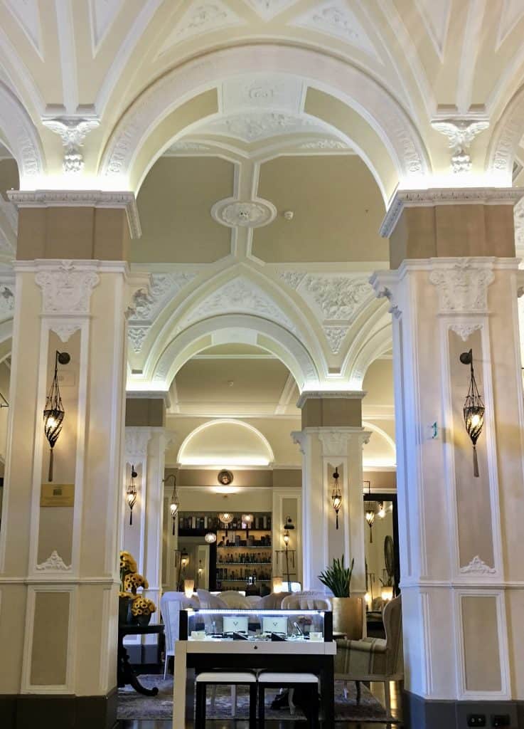 White internal hotel arches which have been opulently decorated in white and gold with french-style chairs and vases of sunflowers.