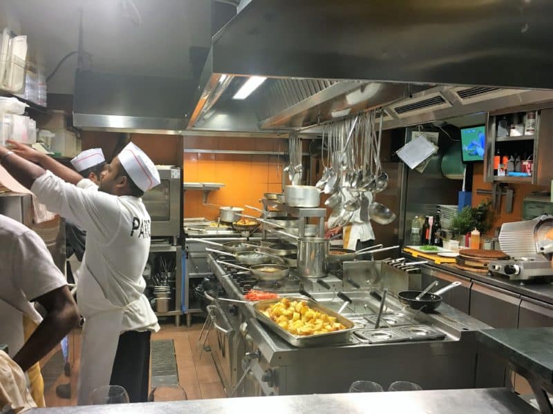 Sampling the fine dining scene in Florence The kitchen space at Parione with chefs cooking to the left and ladles hanging in the central cooking station.