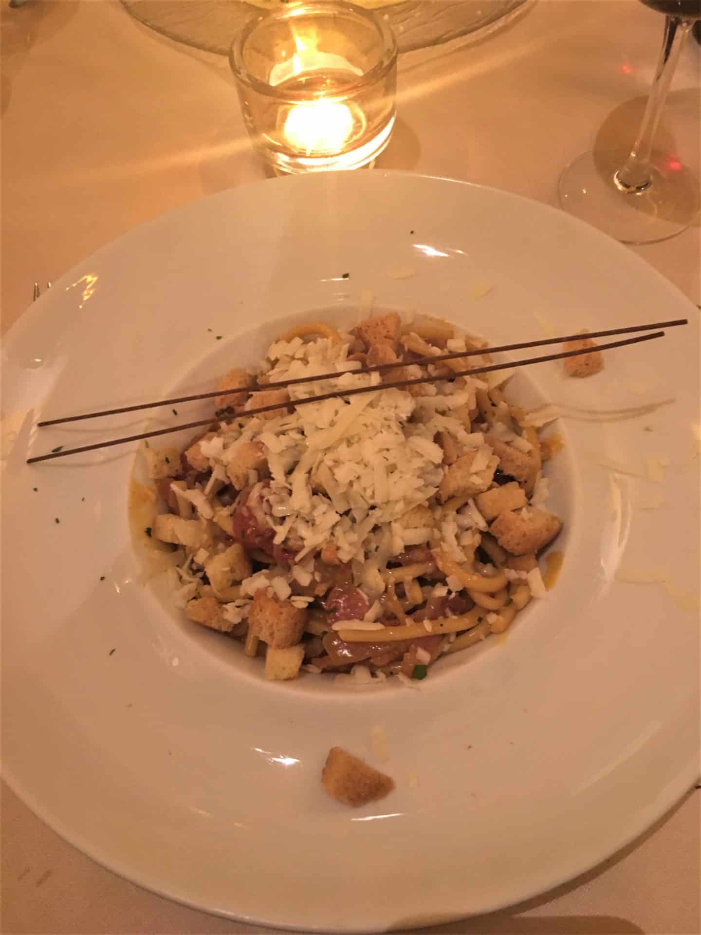 Spaghetti in tomato sauce at Parione with a tea light above it.