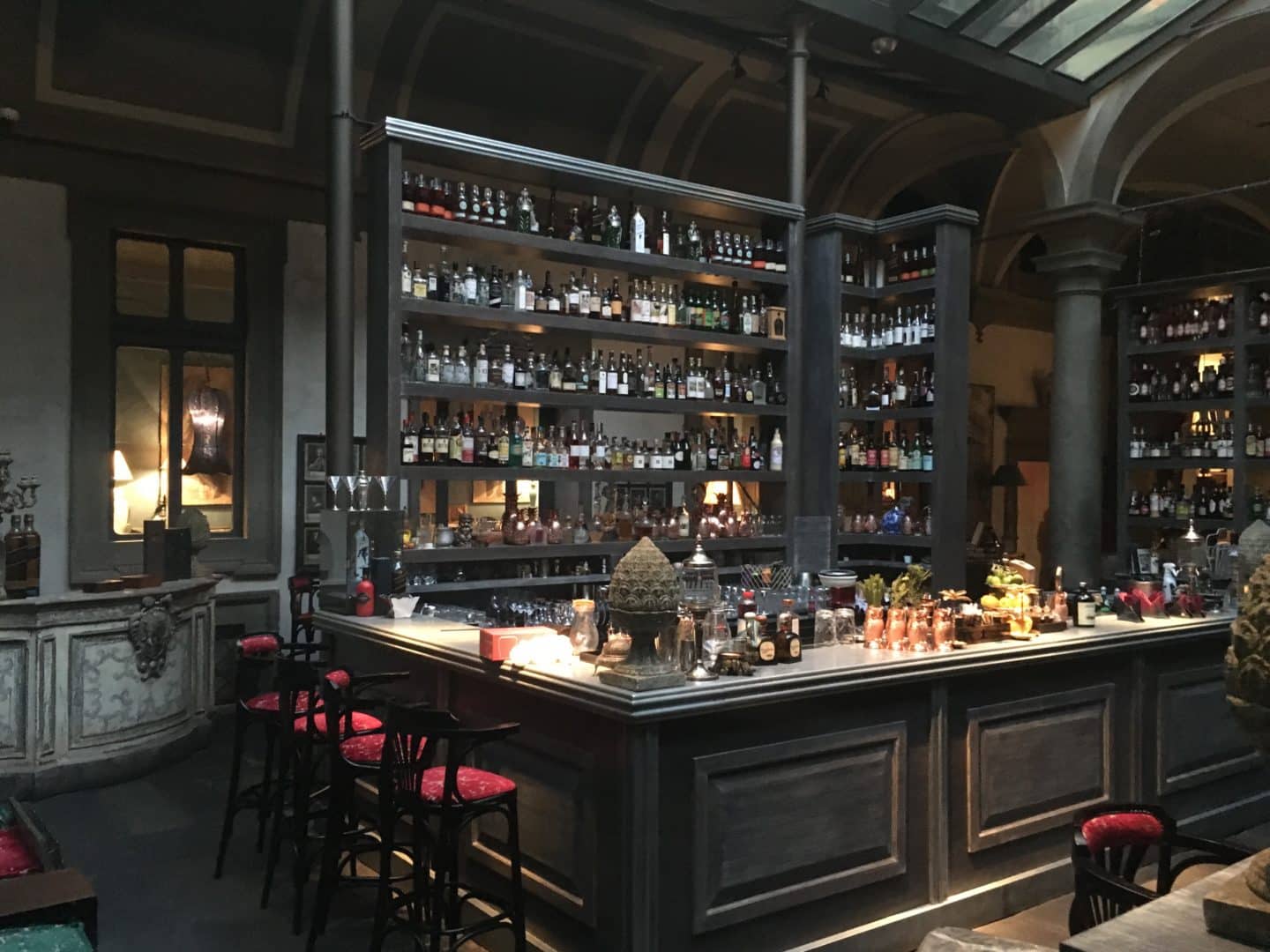 Locale Firenze Bar area which is grey with alcohol bottles lined up and red bar stools