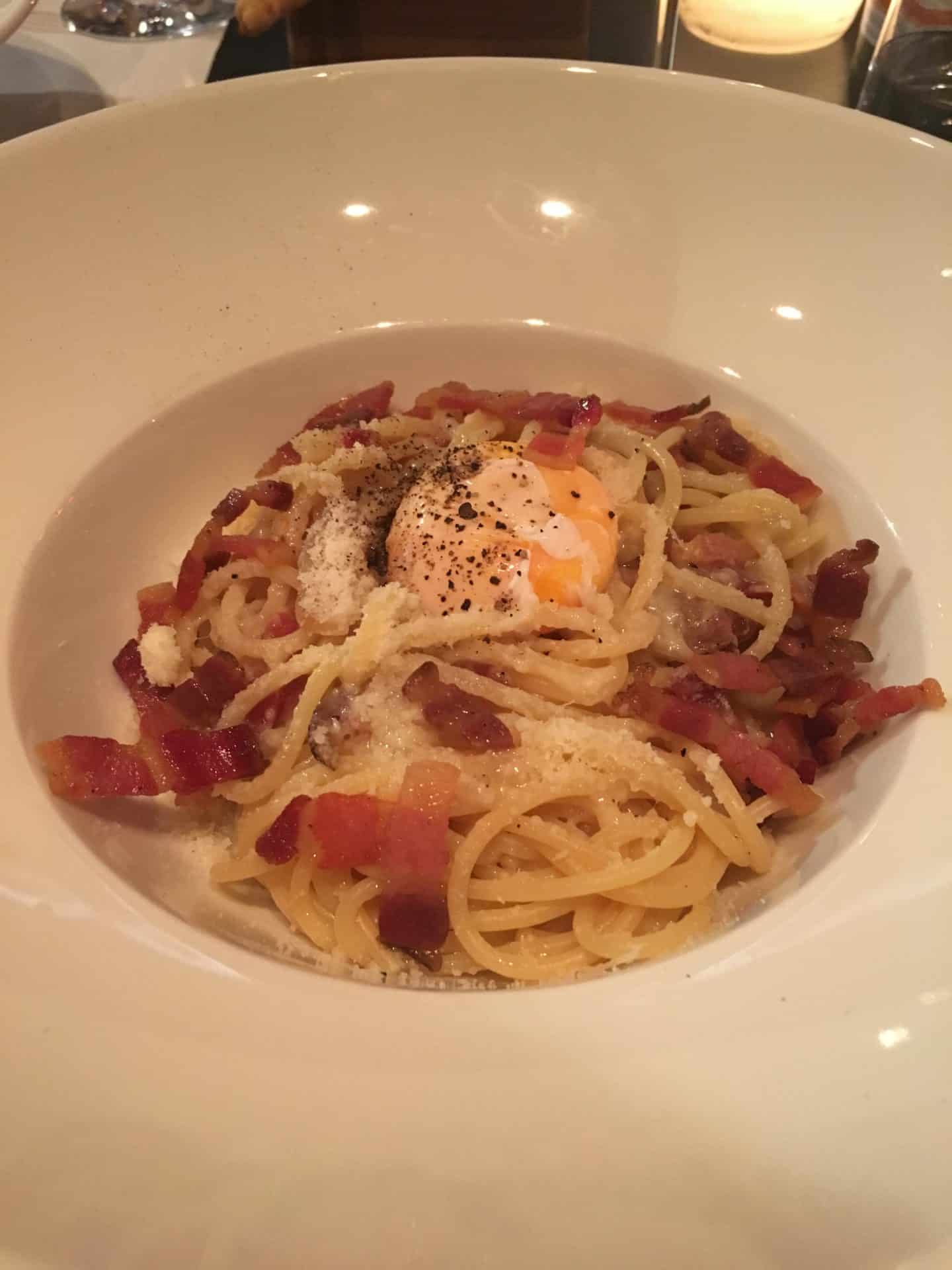 Sampling the Fine Dining Scene in Florence Touch with a bowl of spaghetti with tomato sauce and topped with bacon