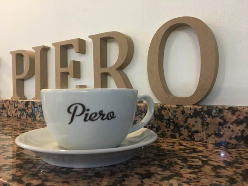 Cup of black coffee with a cup that says 'Piero' Independent Coffee & Cake Locales. Piero's