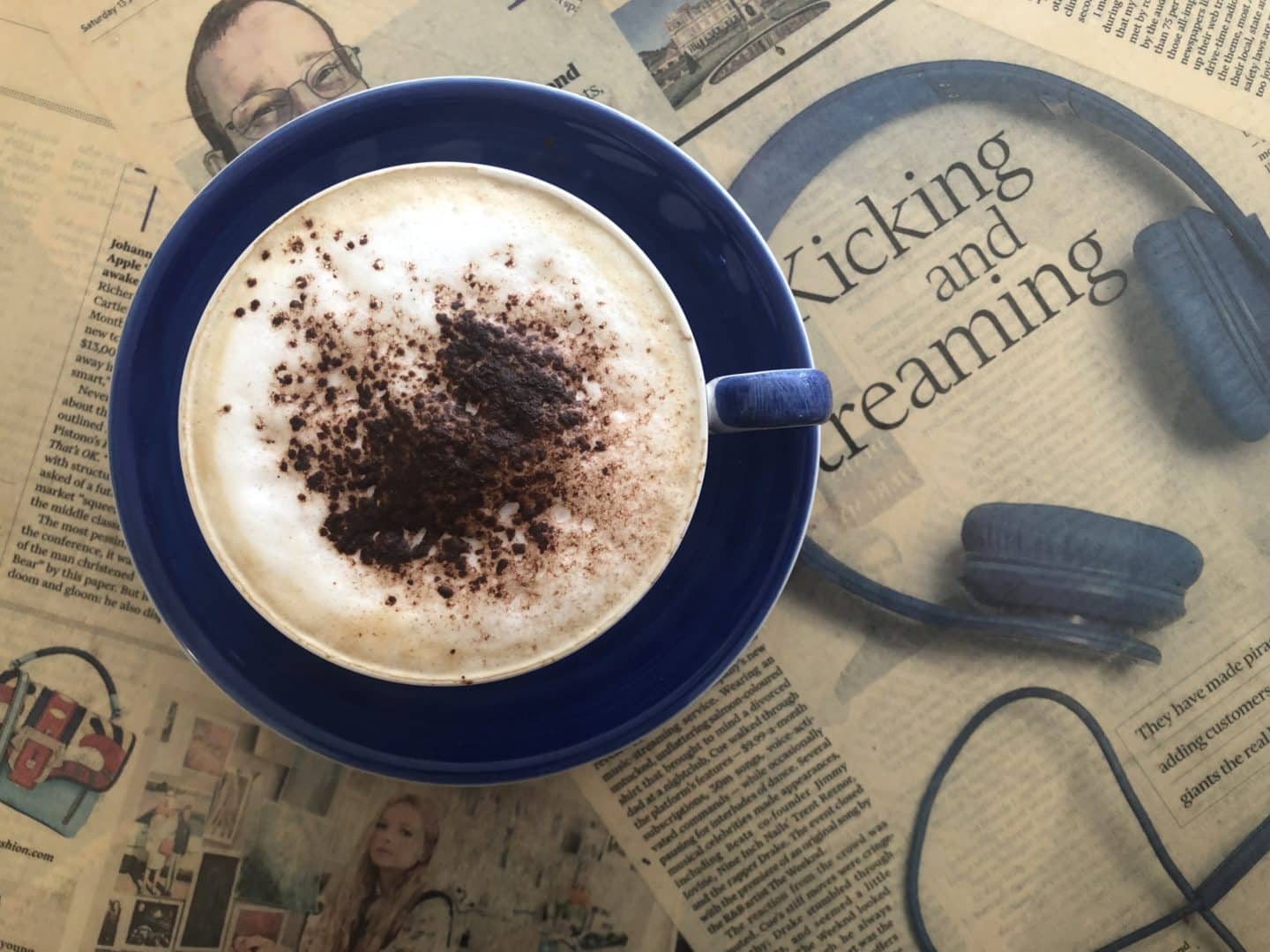 Capuccino Coffee in a blue cup and sauces at James Bistro in Leicester City Centre. There is a newspaper mat below