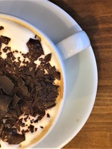 cappuccino Coffee with chocolate sprinkles in a white cup and saucer on a brown table at St. Martin's Coffee in Leicester