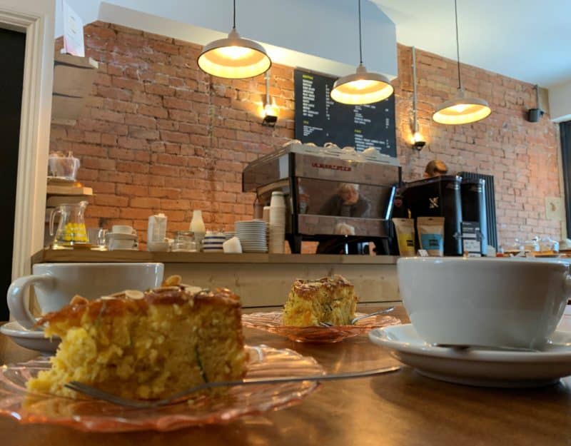 Independent Coffee Shops in LE1, Leicester. The view of the counter at Leicester Coffee House. There are 2 slices of cake and a coffe on the table facing teh counter