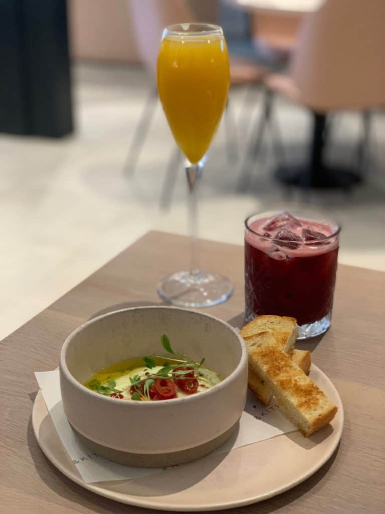 Turkish eggs and non-alcoholic cocktails at &kitch, Leicester. The non-alccoholic cocktail is deep pink in colour and there is also a mango spritz in a champagne flute.