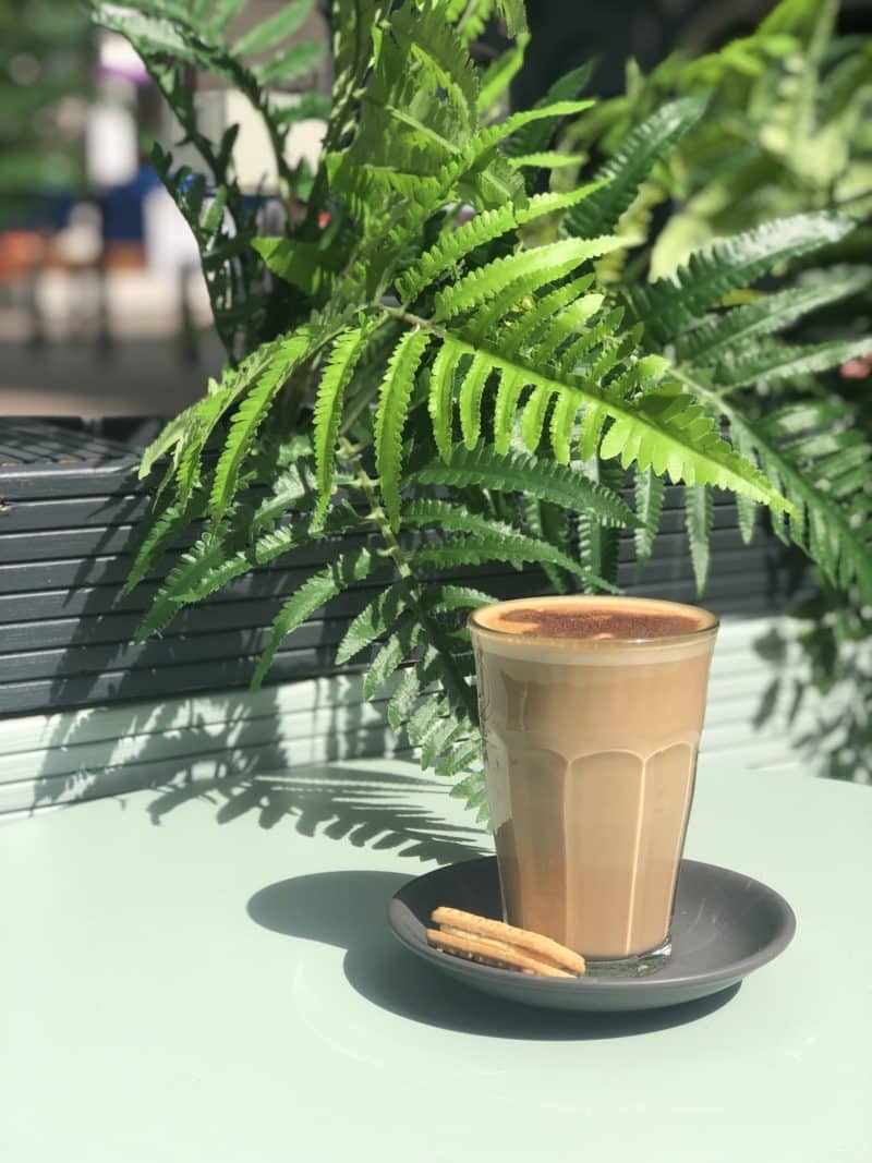 Independent Coffee Shops in LE1, Leicester. A glass with a mocha on a grey saucer and a custard Cream biscuit on the side at Orso Cafe