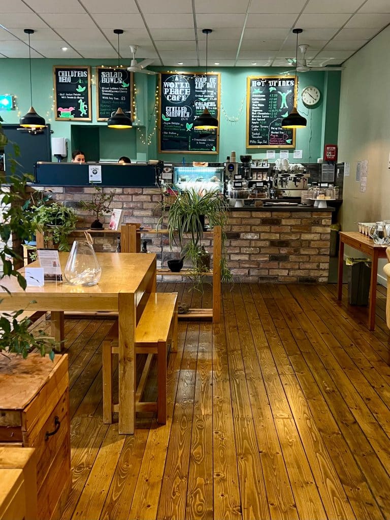 The main counter inside the World Peace Cafe, surrounded by plants and tables with benches