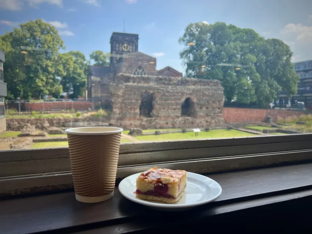 Jewry Wall cafe Leicester. A berrya dn lemon traybake with a cappuccino with views of teh Roman Walls in the background
