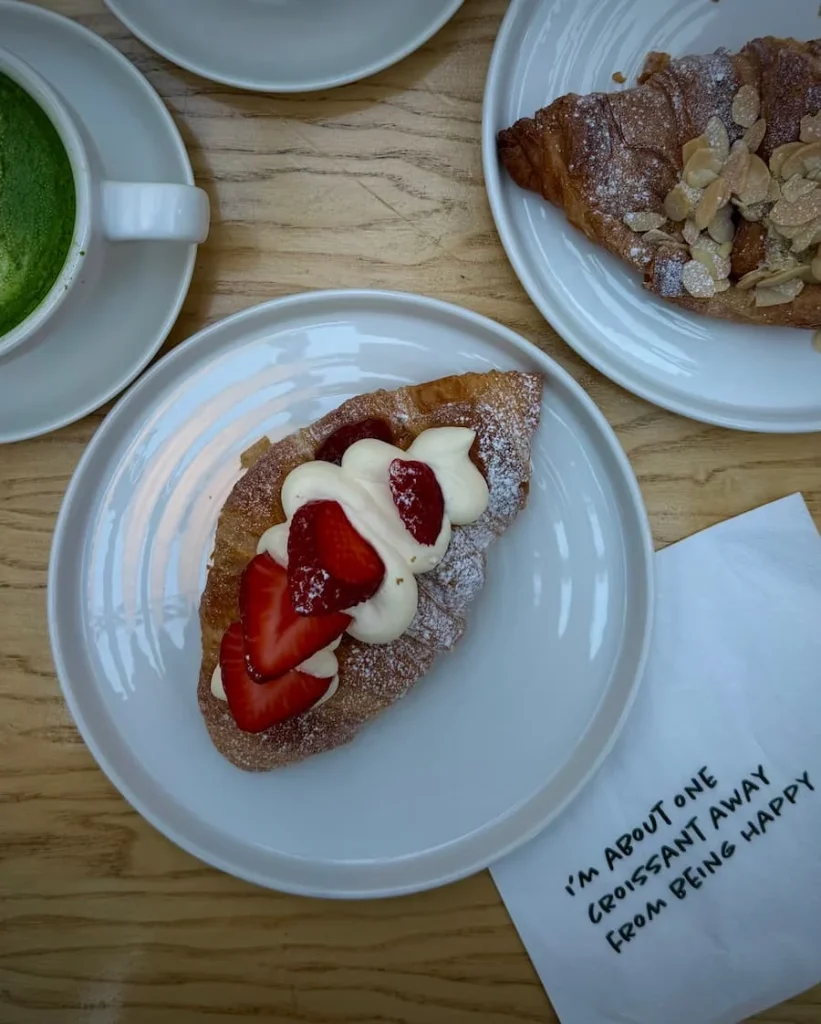 Top lay of Victoria sponge croissant at Public & Plants, Leicester. A cup of Matcha is next to it as well as an almond croissant.
