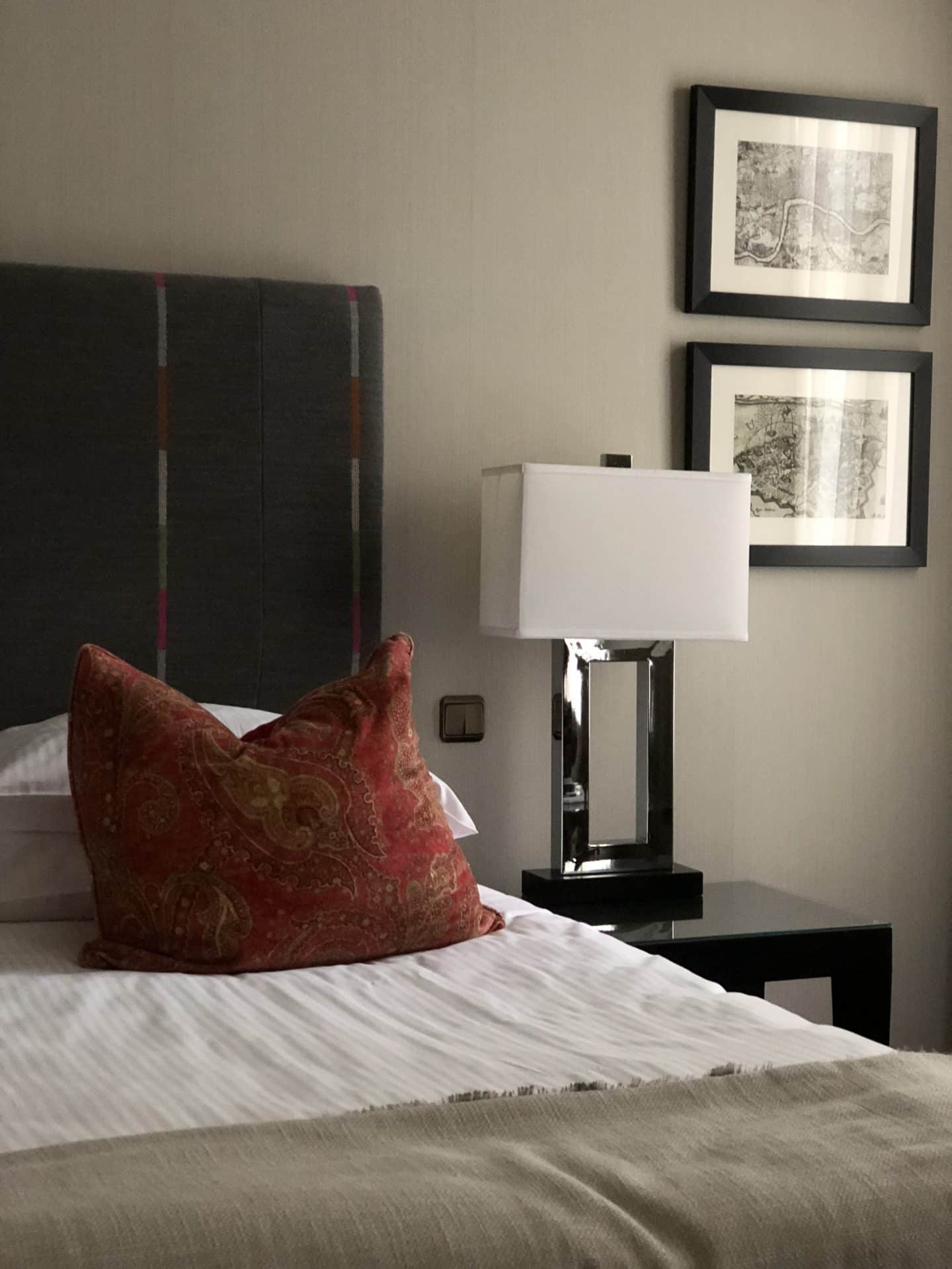 The Grand Palace Hotel Riga with half the bed with red cushion and side table lamp in deluxe room