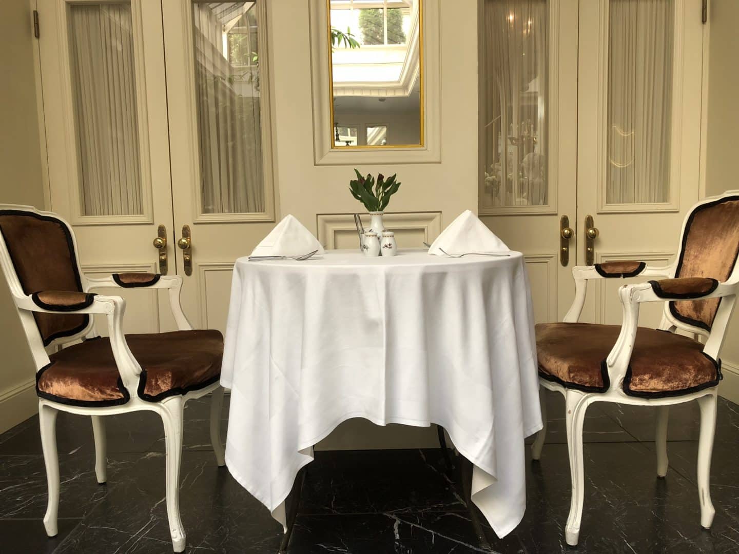 The Grand Palace Hotel Riga Orangery with table and 2 red ornate chairs to the side