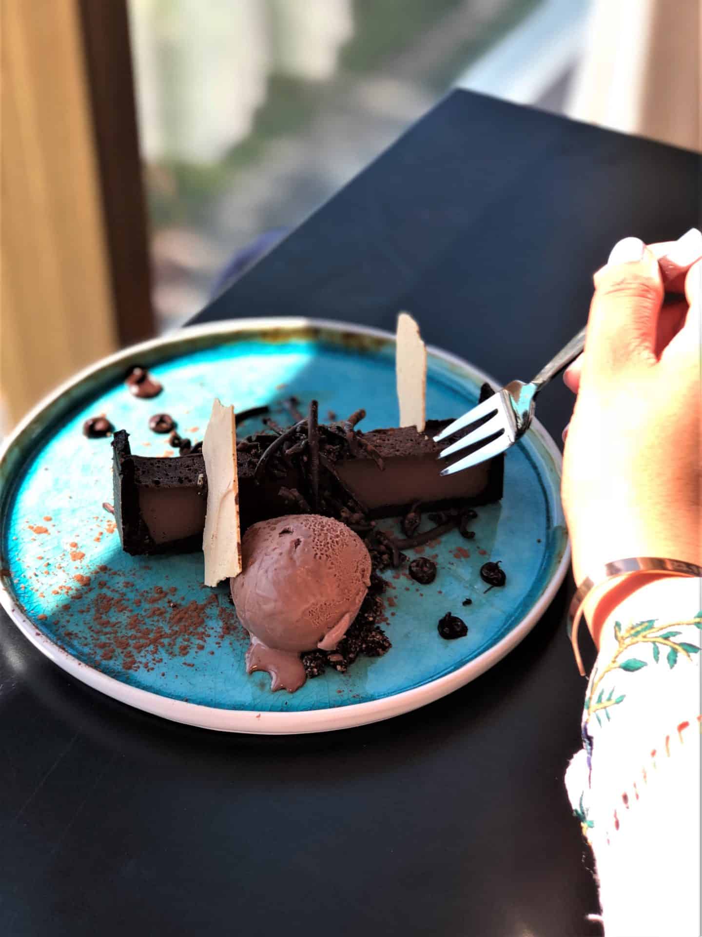Vegetarian-friendly food in Riga: Skyline Bar Riga chocolate torte with chocolate ice-cream dessert which Bejal is cutting through with a fork