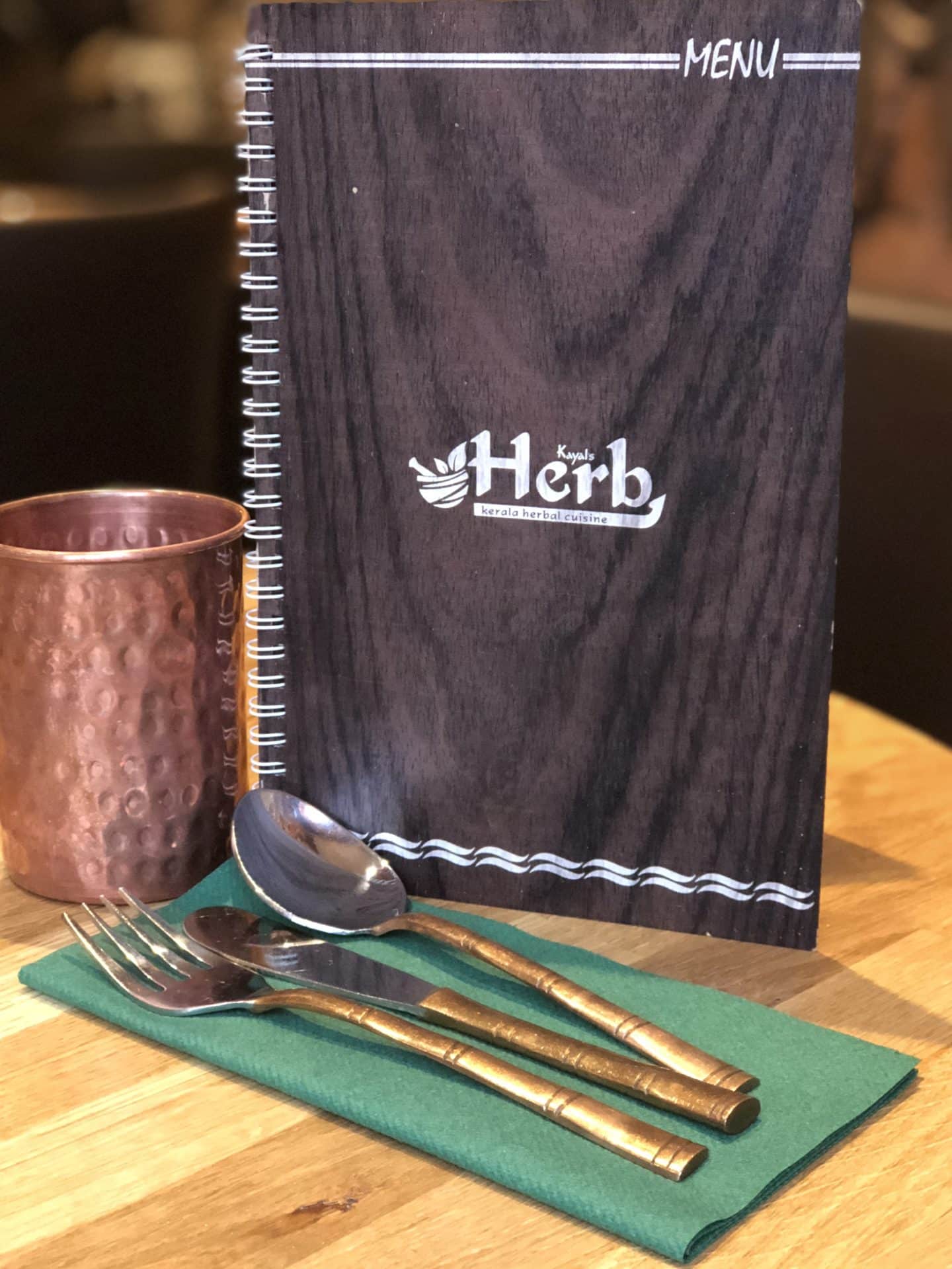Vegetarian Keralan food at Herb Leicester, cutlery and menu with copper cup in the background