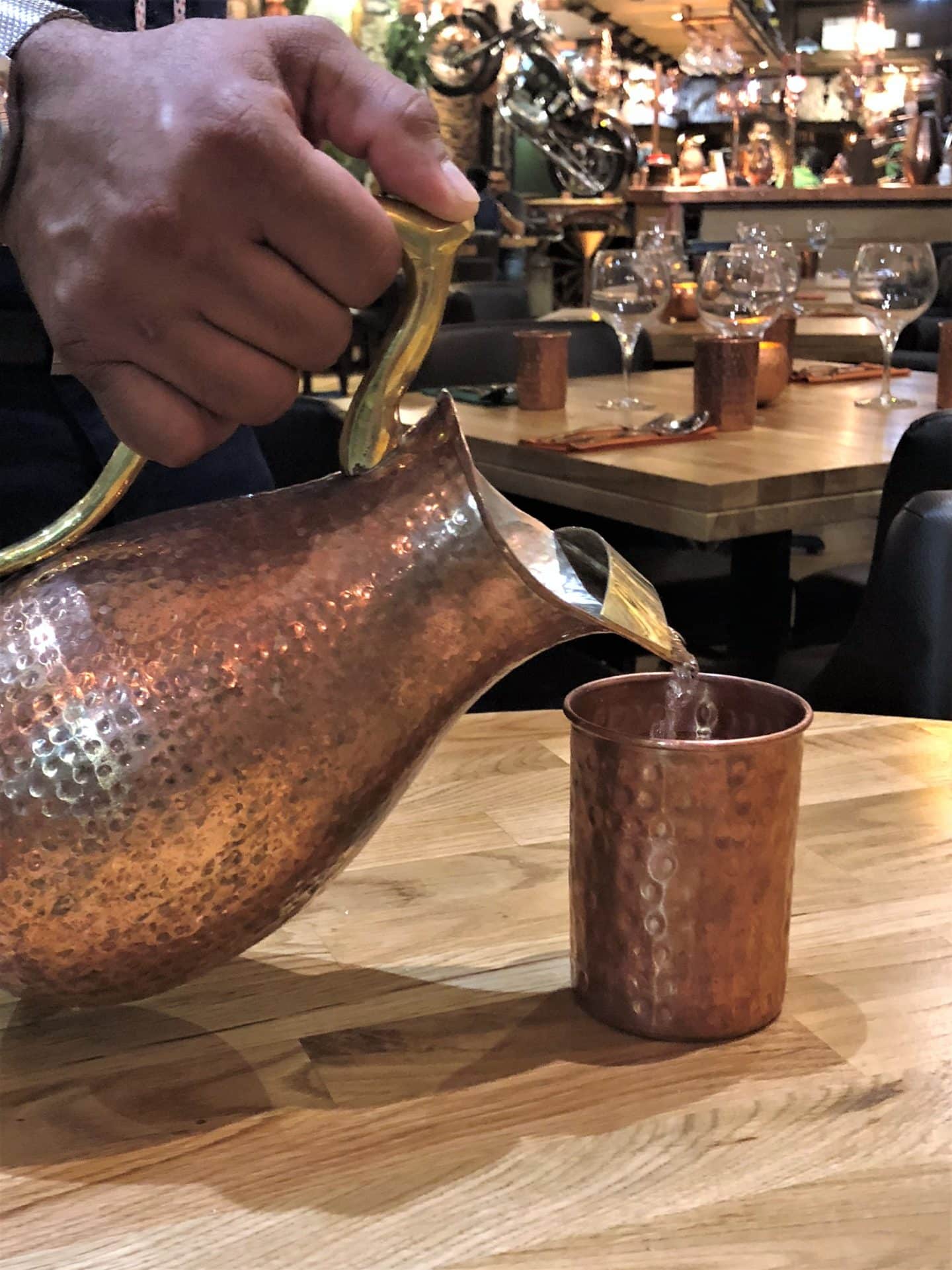 Vegetarian Keralan food at Herb Leicester, water being poured from a copper jug into a copper cup