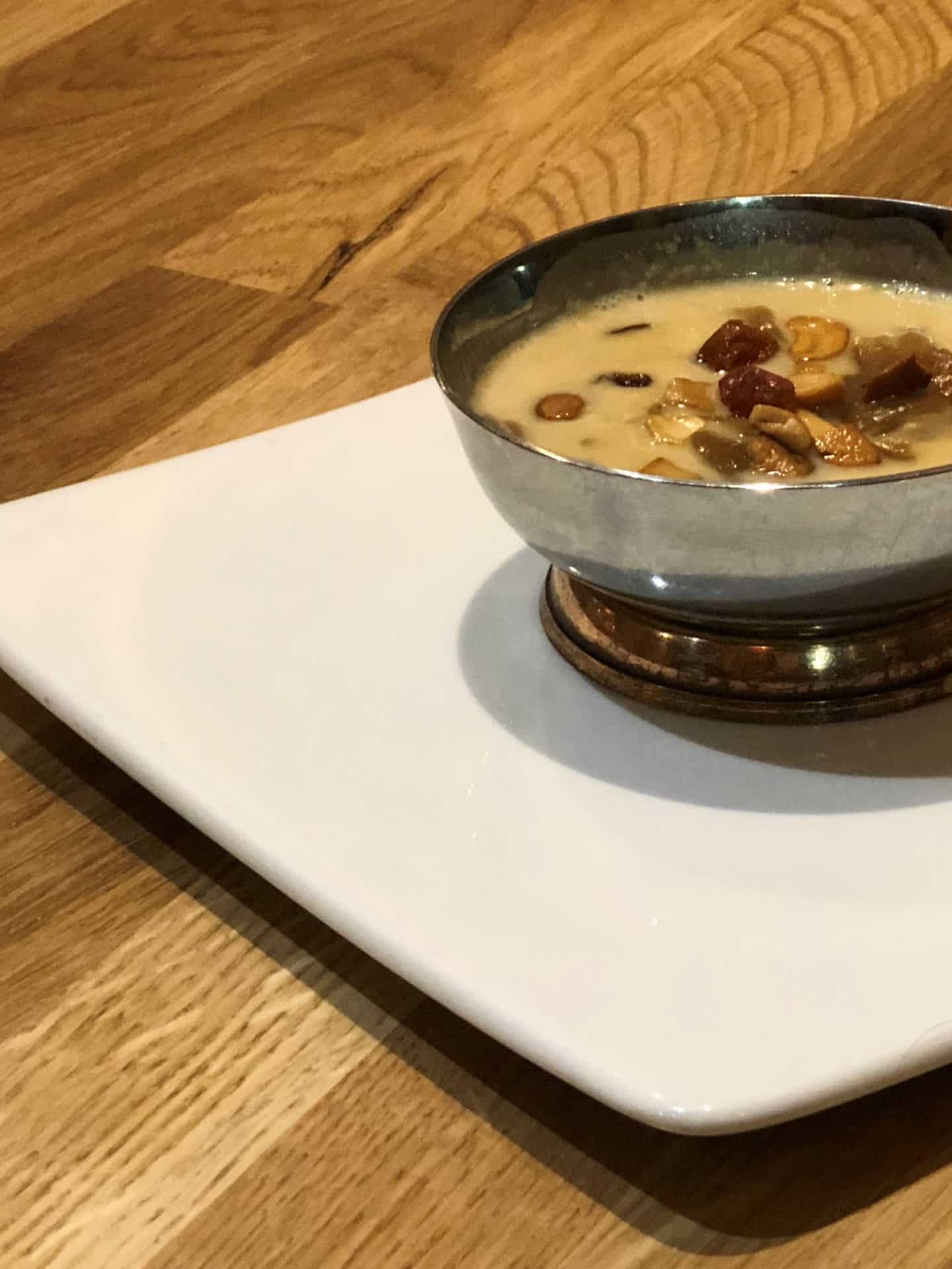 Payasum or vermicelli topped with raisons and nuts served in a steel bowl on a white plate at Herb Leicester