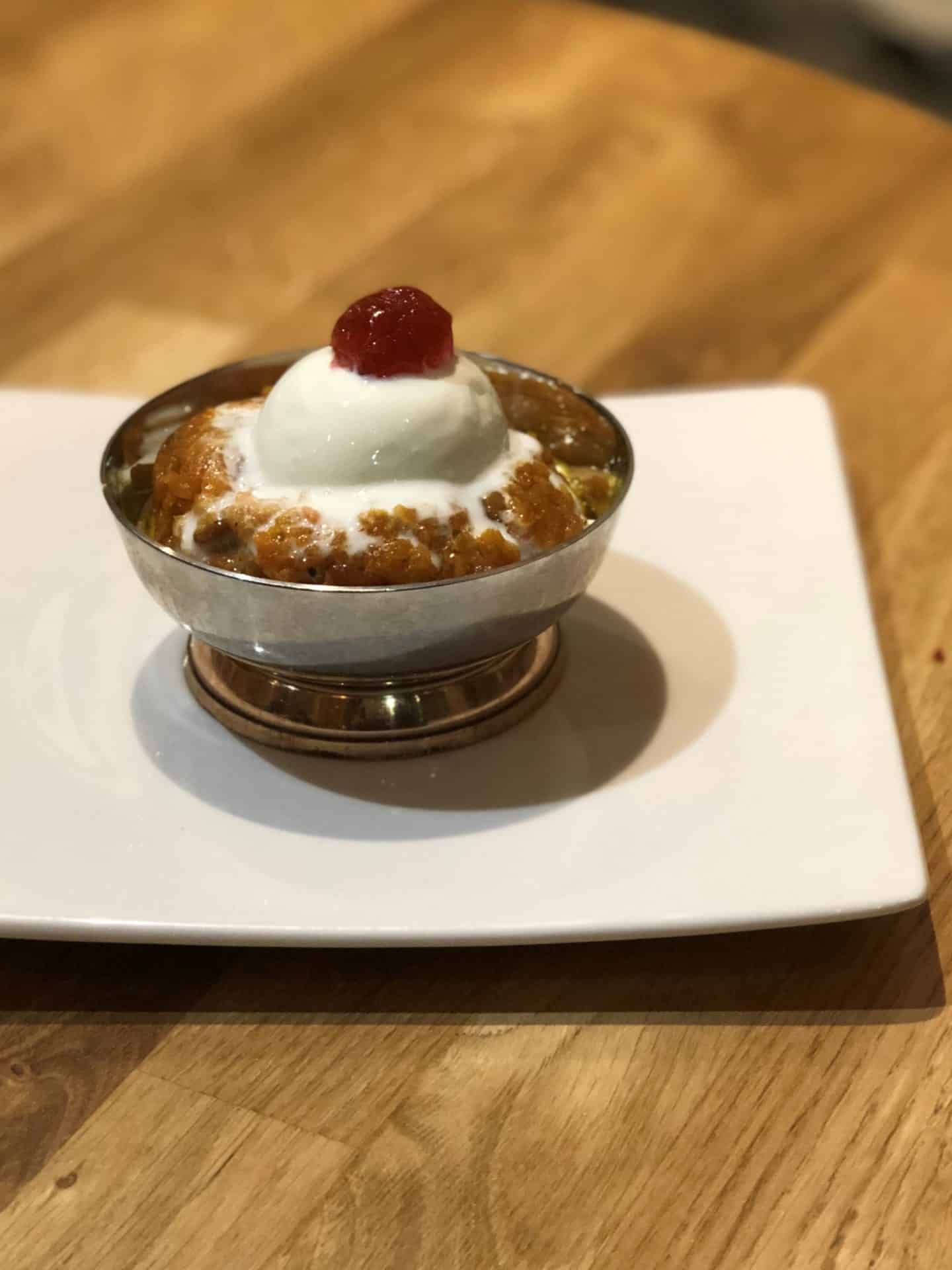 Vegetarian Keralan food at Herb Leicester.  Gajjar Halwa topped with a cherry on a white plate