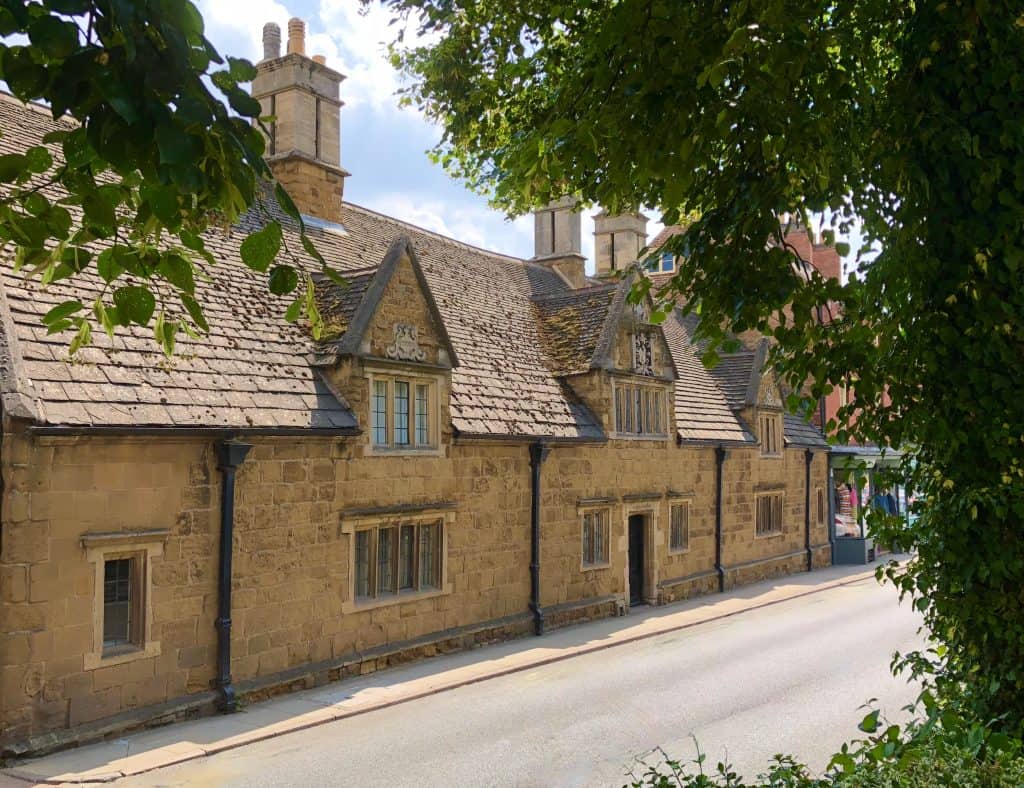 Melton Mowbray, Leicestershire, Bede House made from local stone in a sand colour with the photo framed with trees and green foliage