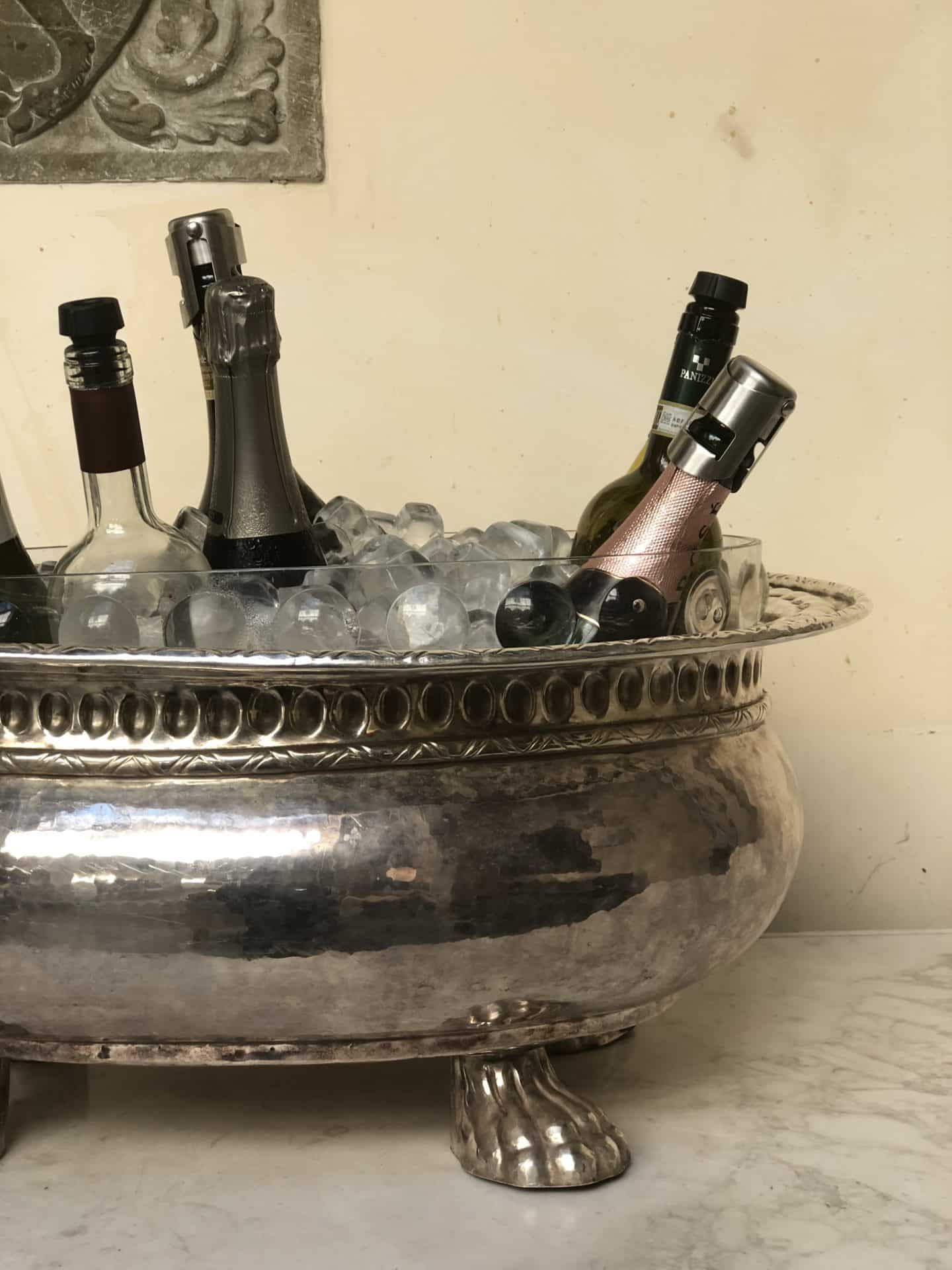 A silver ice filled container filled with water and bottles of prosecco.