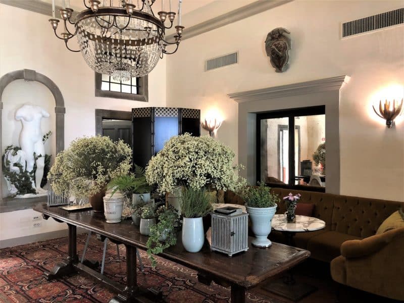 Stunning luxury hotel in Fiesole: A small lean to room on the ground floor with a dark wood table upon which are vases of gypsophila