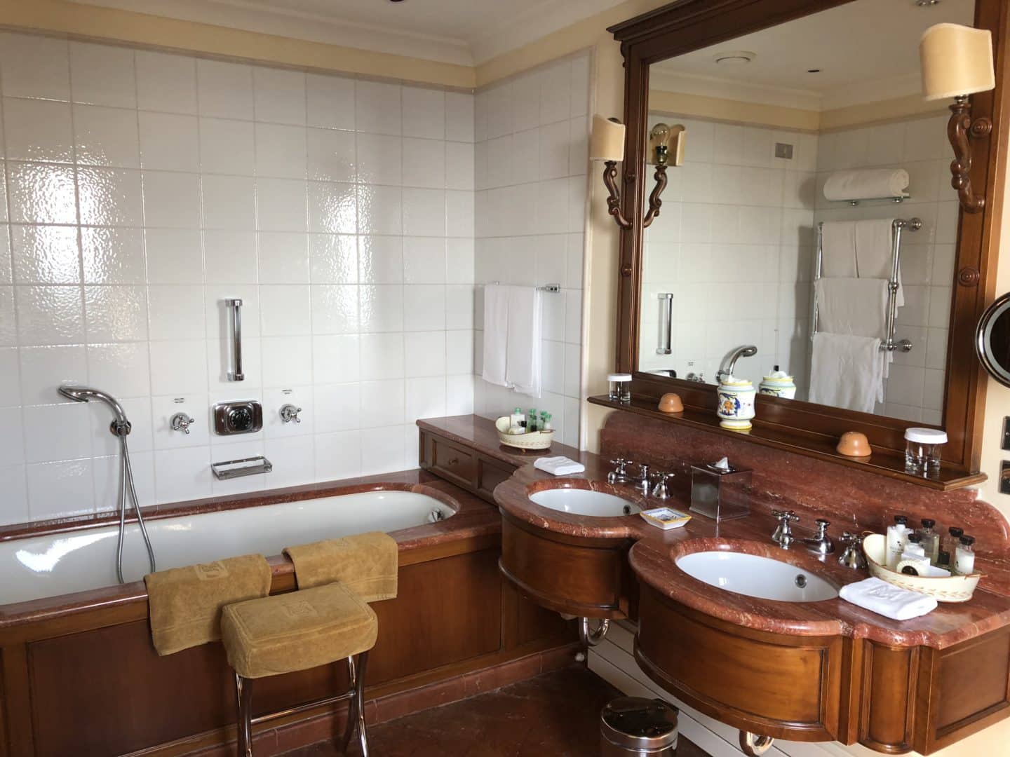 A stunning luxury hotel in Fiesole: dark wood bathroom with Bvlgari toiletries, deep sunken bath and wash basins.  
