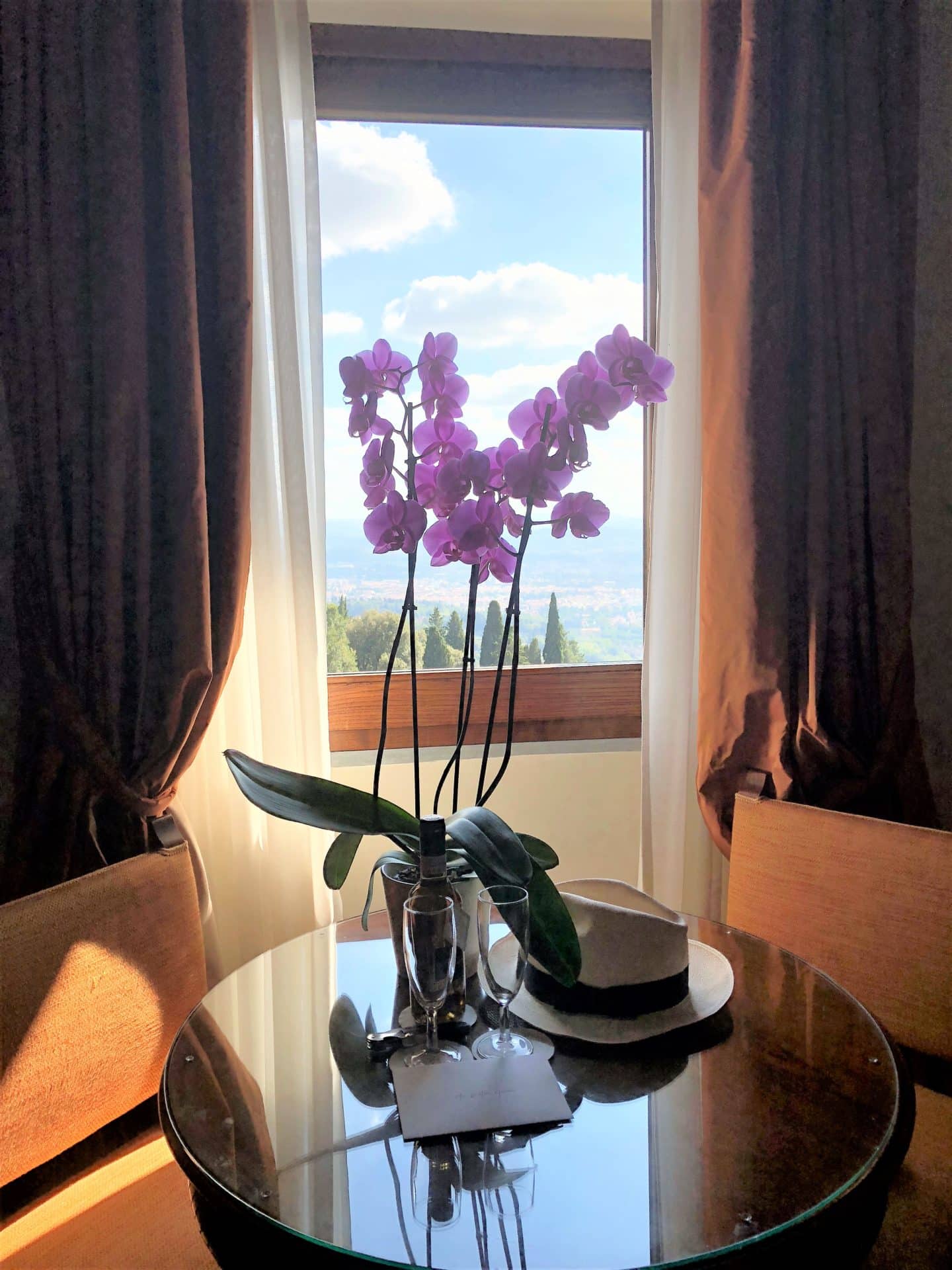 Dark pink orchid in a vase on table in front of a window in the bedroom overlooking Florence.
