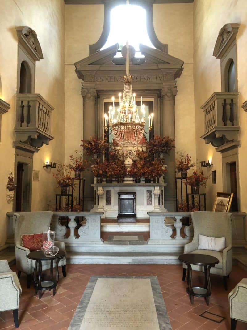 A stunning luxury hotel in Fiesole: entrance hallway , old part of the church with a big crystal chandelier hanging in the middle of teh ceiling.