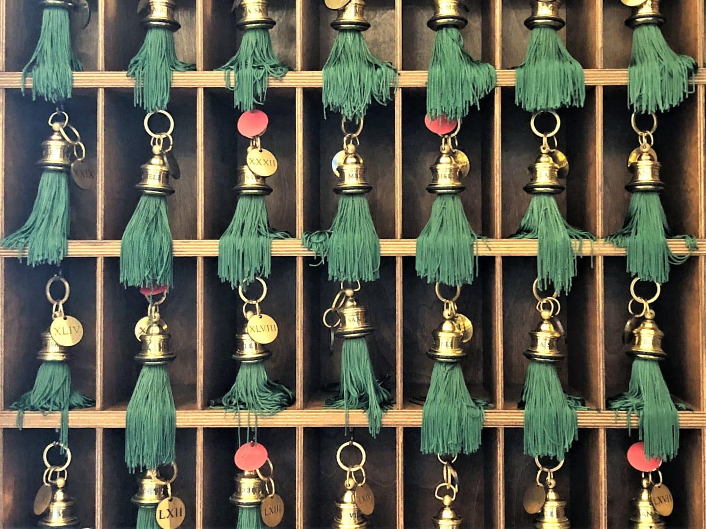 Belmond Villa San Michele: A stunning luxury hotel in Fiesole. A wooden grid of door keys which are gold with bright green tassles. They are all neatly stacked in teh hotels reception.
