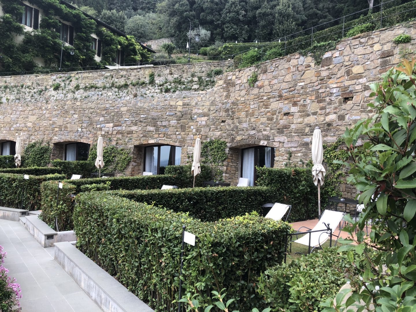 A stunning luxury hotel in Fiesole: stone and brick wall with garden room doors and hedged gardens for privacy 