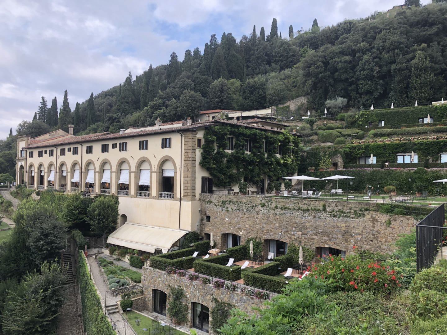 Side view of Belmond Villa San Michele main cloister house with suites on the lower level and gardens to the lower level also.pink flowers, trees and shrubs on th ebottom level.