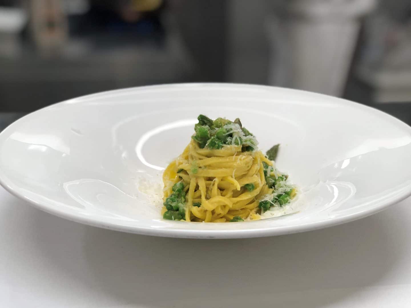 A Private Cooking Class at Touch Bistro, Florence - A white plate swith tagliatelle and a peak and rocket sauce topped with parmesan.