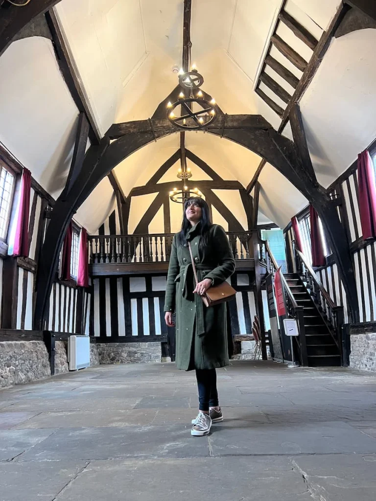 Bejal standing inside Guildhall with a beamed ceiling and a staircase behind her