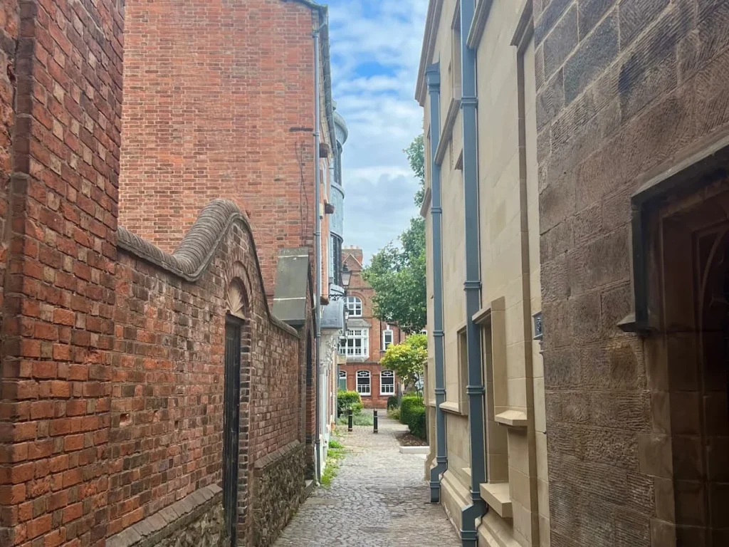 Cathedral Lanes in Leicester City Centre. Image taken from the side of the cathedral with historic buildings peeping through via the cobbled-stone street.