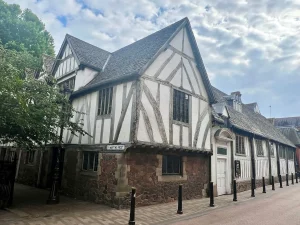 The Black and white exterior of the Guildlhall with black bollards in front and trees to the right hand side