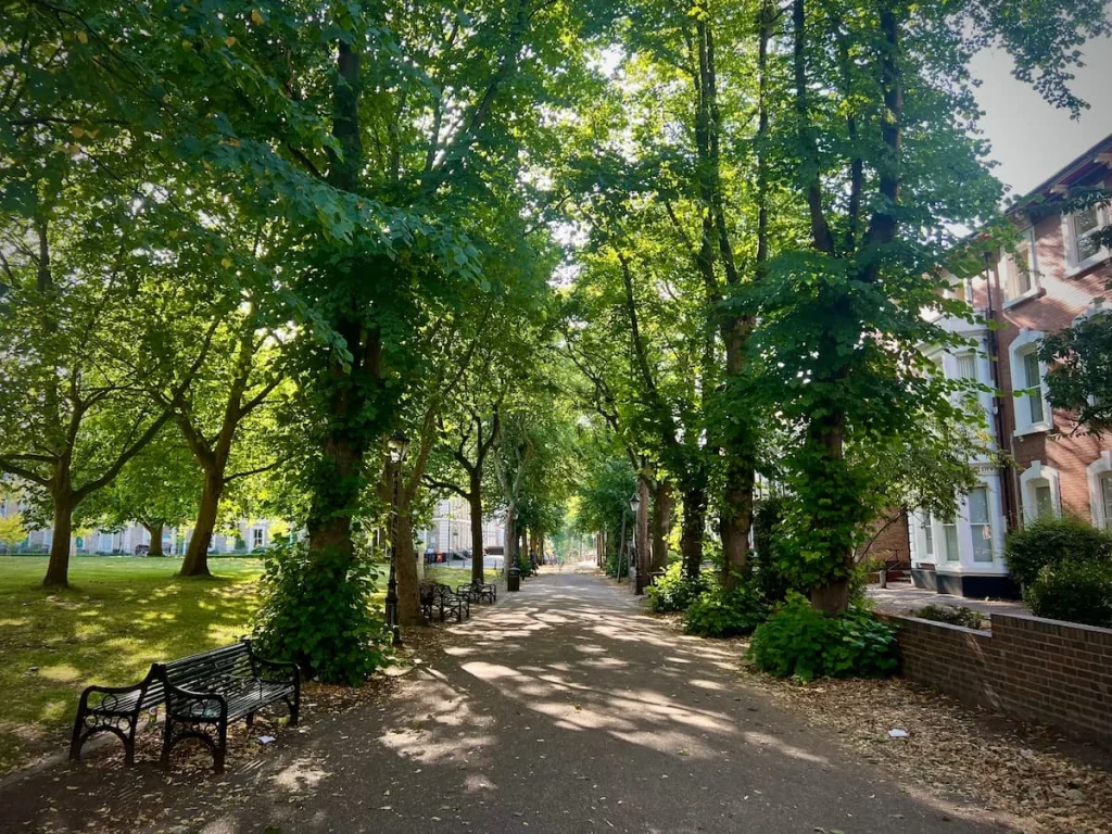 New Walk De Montfort Square to the left and victorian houses to the right with a leafy path in the middle and trees framing both sides.