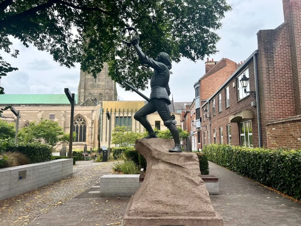 Richard III Statue with Leicester Cathedral in the background and a tree on the left hand side. There are Diocese houses to the right