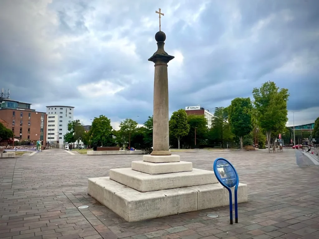The High cross monument, Leicester. The cross is made from stone with a metal top and 3 stepped levels. It's located on Jubilee Square in Leicester city centre