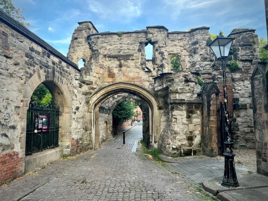The medieval stone constructed Turrett Gateway with cobbled-stone streets, Victorian lights and blue skies behind it