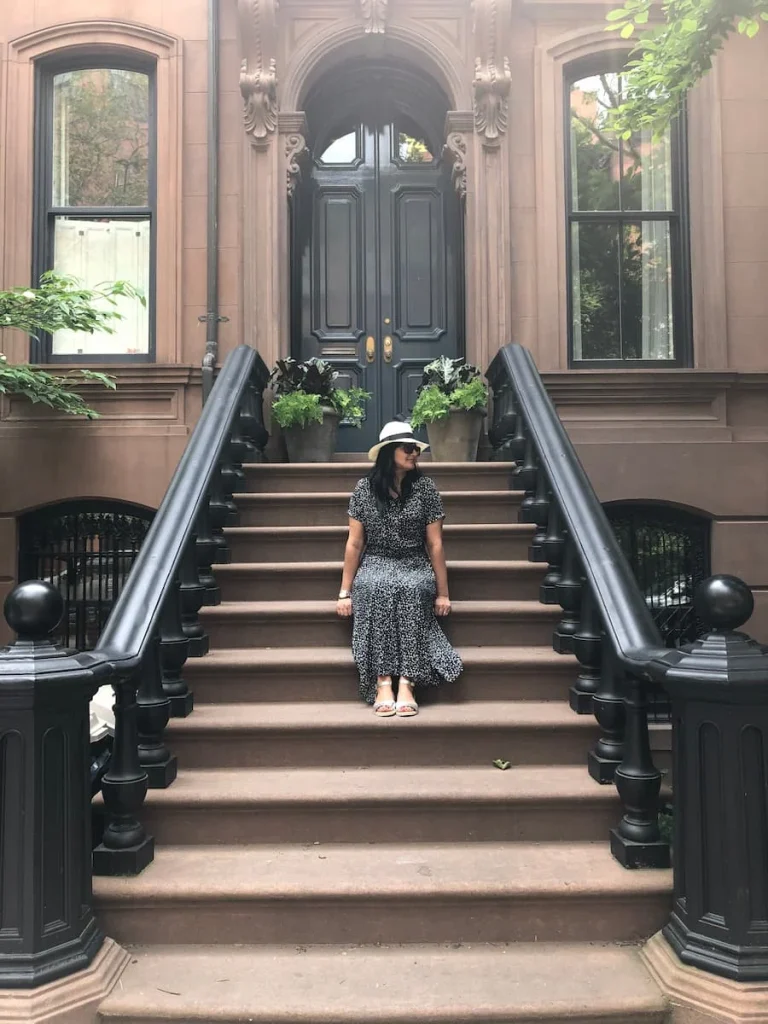 Bejal sitting on steps on a brown stone house in Greenwich village, NYC