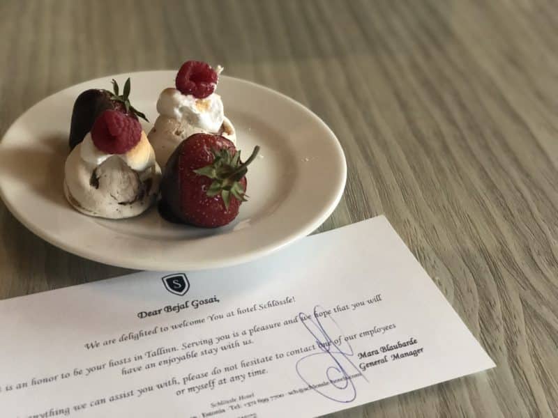 The Schlossle Hotel Tallinn: A white plate containing white chocolate covered strawberries and raspberries accompanied by a welcome note from the manager in the deluxe garden suite.