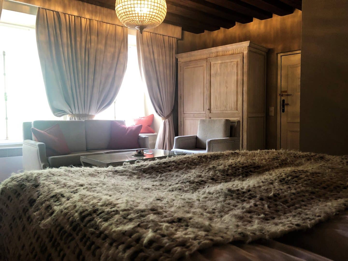 The Schlossle Hotel Tallinn: A view from the bed of the grey finish wardrobe and sofas with the curtains and window seats in the background