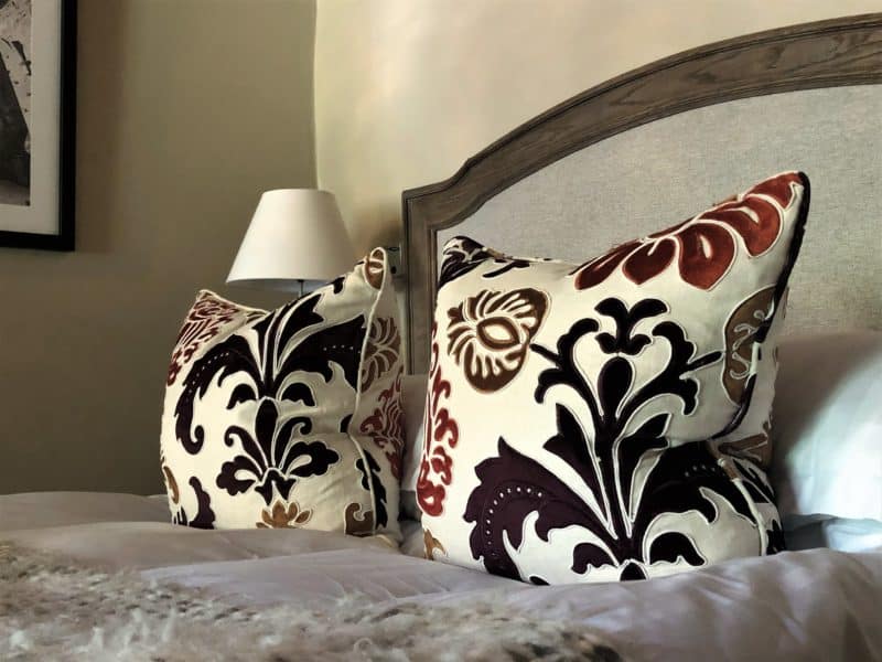 The Schlossle Hotel Tallinn: The black and maroon floral patterned scatter cushions on the bed in the Deluxe garden Room 