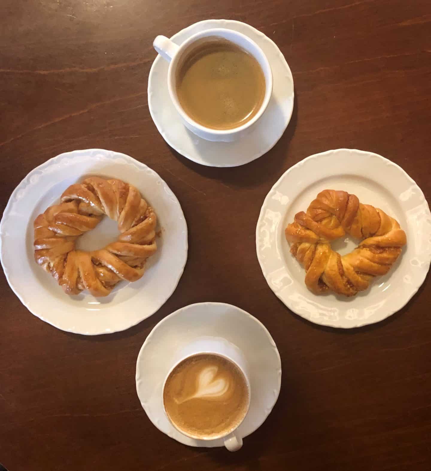 Flat lay of coffees and Estonian pastries at Maiasmokk cafe in Old Town Tallinn. They are placed on a mid-brown coloured table. 