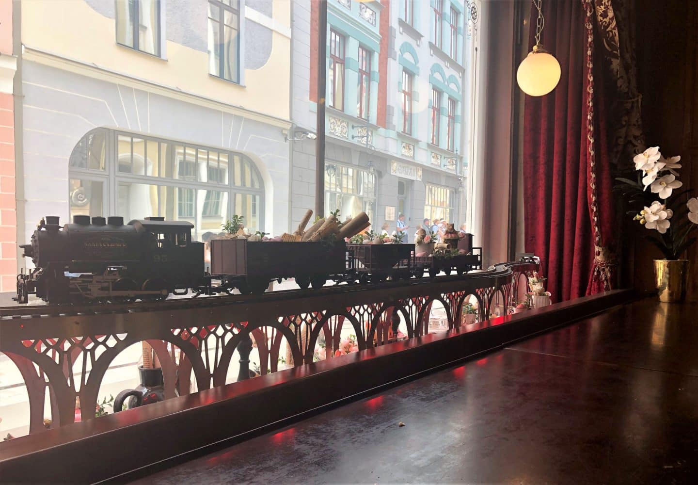 Play train on the window sill of Maiasmokk cafe in Tallinn, the window is framed by velvet red curains