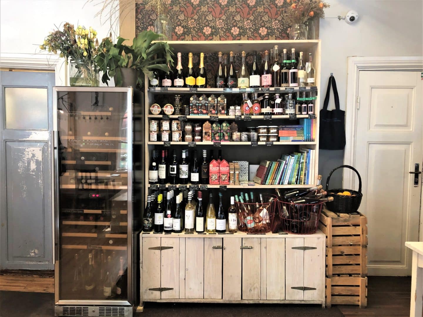 A drinks side board at the Nop Cafe shop in Tallinn. the cabinet is full of different bottles of drinks and teher are other crates and drinks in the background.