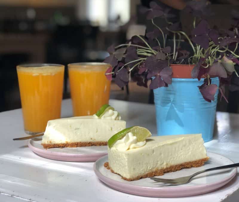 Line cheesecakes with freshly squeezed orange juice at NOP cafe in Tallinn. There's a plant in the background with a blue plant pot. 