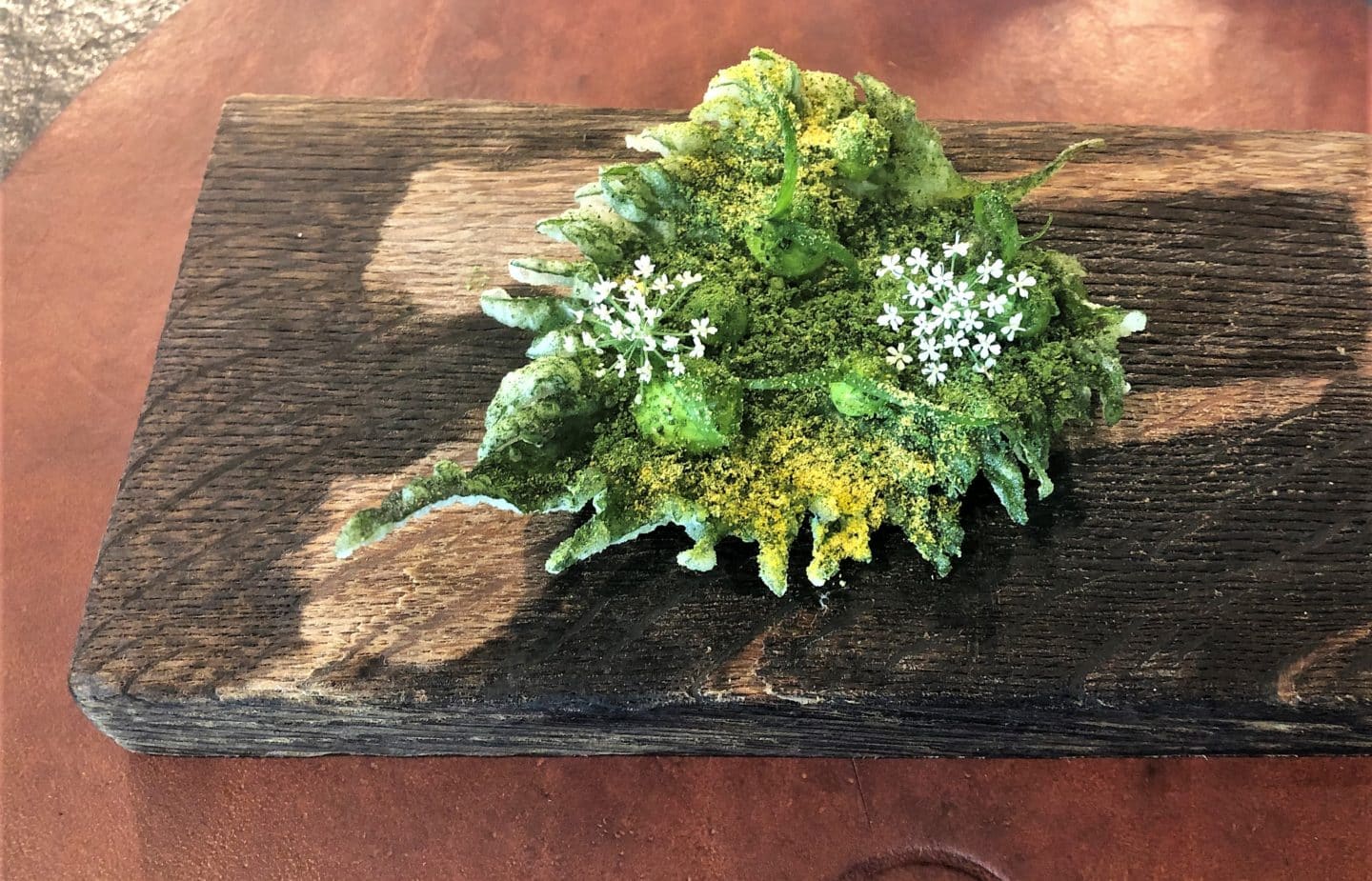 Edible flowers on a wood board, scattered with spring onions at Noa Chef's Hall, Tallinn