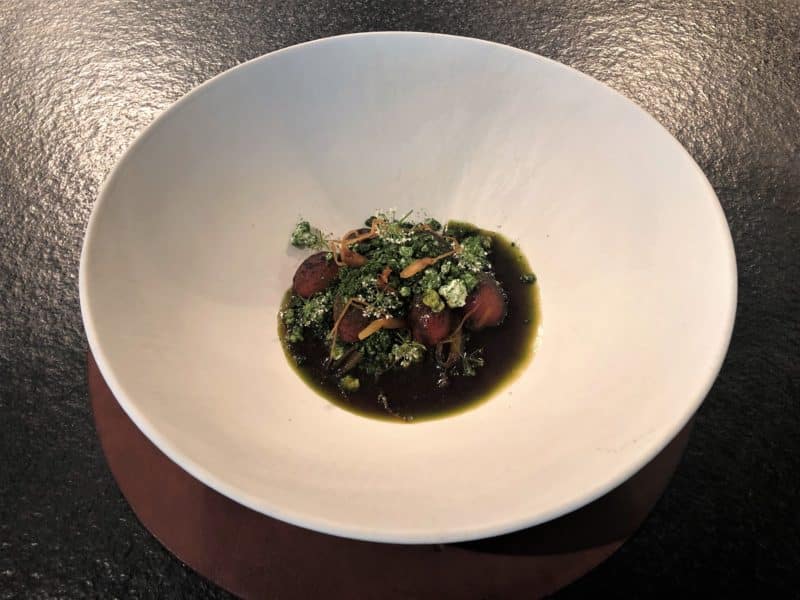 Cherry tomatoes with goats cheese at Noa Chef's Hall Tallinn. the ingredients are in a wide white deep bowl contrasting the black counter.
