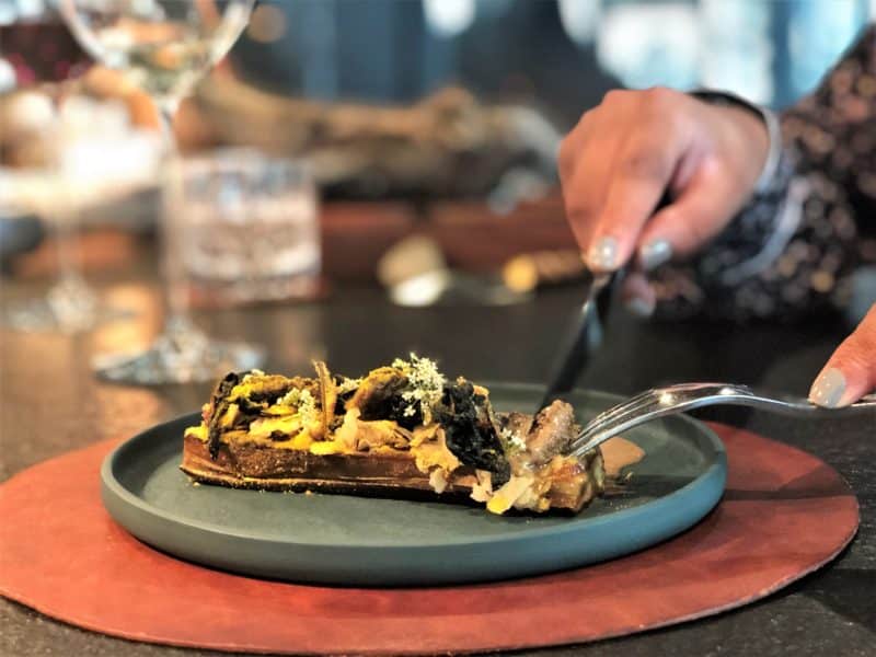 Bejal cutting into the delicate mushrooms served with wild garlic roots and a porcini mushroom sauce at Noa Chef's Hall Tallinn